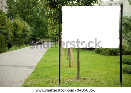 Blank billboard on green grass in park to place your logo or advertising on it