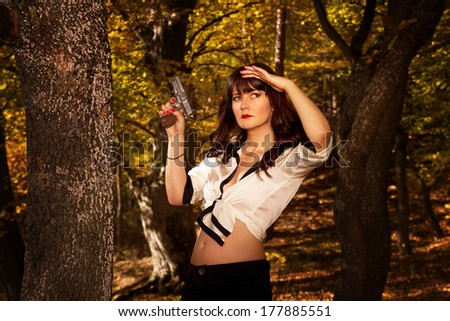 Brunette woman with a pistol/ gun in forest