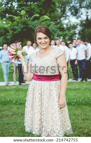 Happy young beautiful woman holding the bride bouquet on near her shoulder