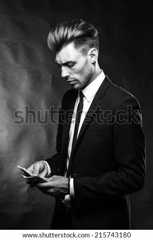 brunette handsome man in a suit on a dark background with money