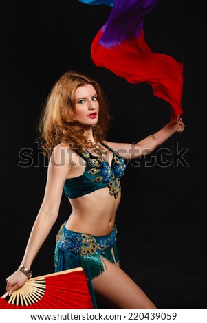 woman in carnival costume with a fan on black. belly dance