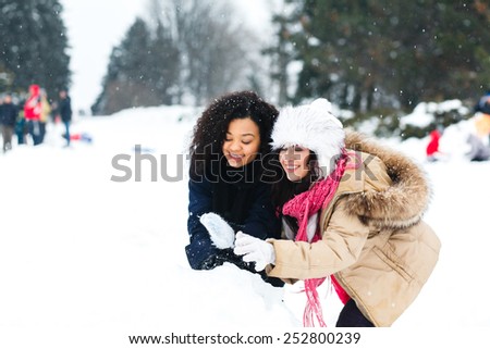 Two joyful and energetic friends playing games and having fun, having a snow ball fight in the snow mountains landscape during a skiing holiday on a sunny winter day, outdoors.