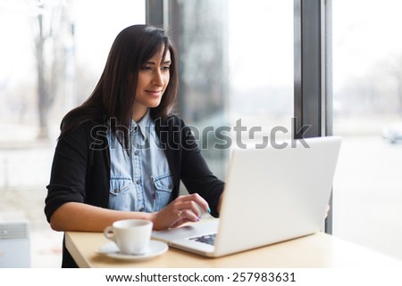 woman siting with coffee and using laptop in cafe