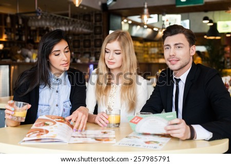 three friends in a cafe make the order. lifestyle. beautiful people