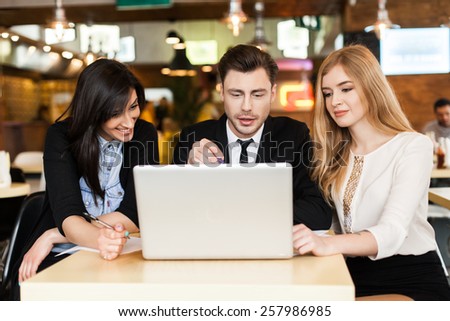 Group of young smiling business people, siting in cafe, using laptop. rest and work. business people smiling at the camera