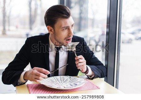 businessman male eating his money, concept. eats dollars. handsome businessman makes a lot of money
