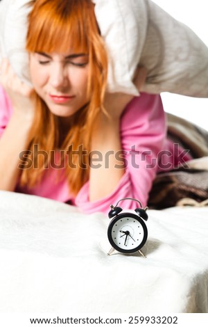 alarm clock. Young woman in the background covering ears with pillow. room clock bed lazy sleep wake alert
