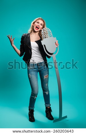 girl having fun in the studio with a fake microphone. musical instruments, concept, rock, blonde