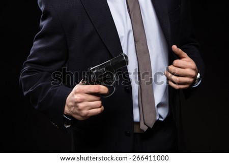 a man with a gun in studio. weapons, crime. businessman with a gun