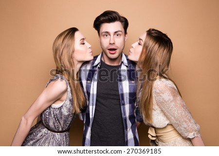 Two women and an handsome guy, Love triangle. Two young women kissing to the man.