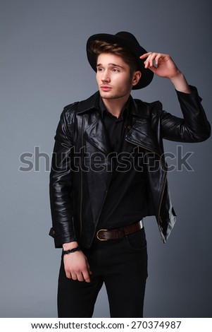 fashion guy in the studio, attractive man, hat, leather jacket, style