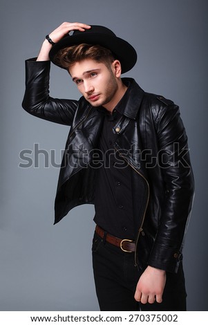 fashion guy in the studio, attractive man, hat, leather jacket, style
