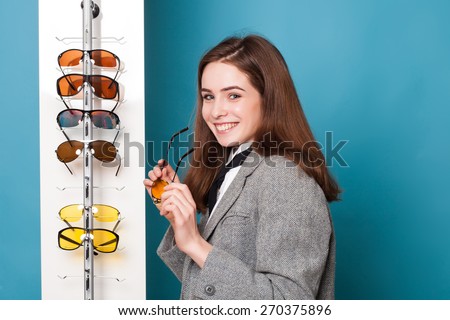 Happy young woman trying new glasses at optician store
