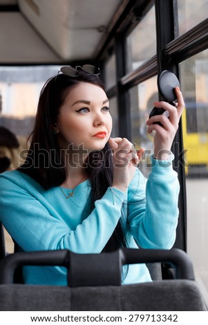 girl brings herself up, looks in the mirror, adjusts makeup in public transport, bus