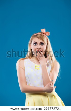 beautiful girl in the studio on a blue background in the style of pin-up, in a yellow dress, flirting, showing different emotions