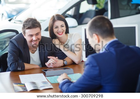 Now her dream comes true. Car salesman giving the key of the new car to the young attractive owners