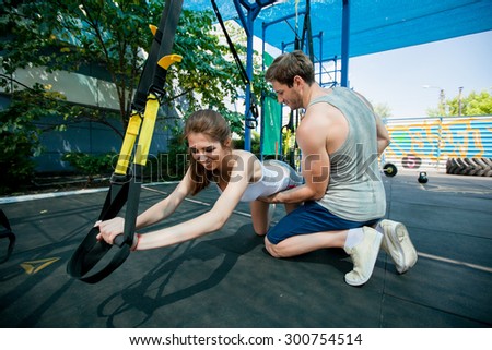 Man during workout with suspension straps on the street. Trx