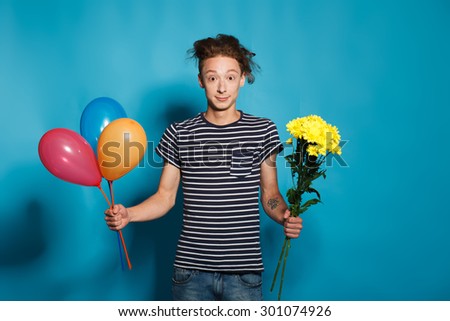portrait of a young man blowing a balloon over a blue background
