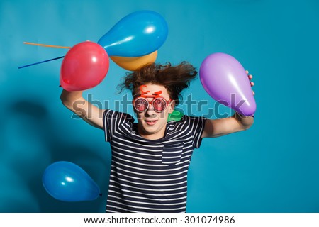 portrait of a young man blowing a balloon over a blue background