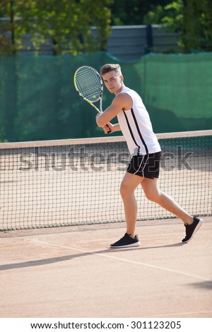 young man play tennis outdoor on orange tennis court
