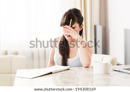 Young woman having headache, leaning on table, rubbing eyes