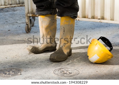 Worker\'s muddy boots and helmet,  worker taking a break