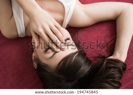Young tired beautiful woman having headache, rubbing eyes in bed