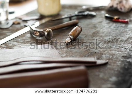 Leather crafting tools on working desk with a low depth of field