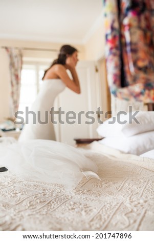 A bride gets dressed in formal wear. Bride\'s veil in front on the bed. bride preparing for a wedding.