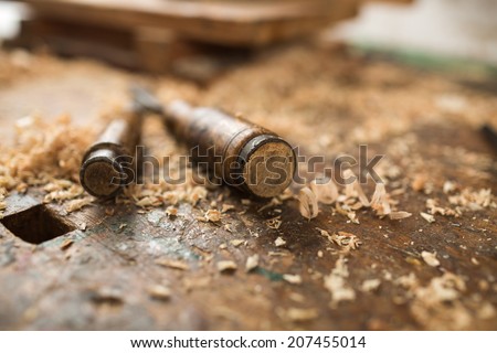 Composition of two antique chisels and wood chips on the working desk in wood workshop.
