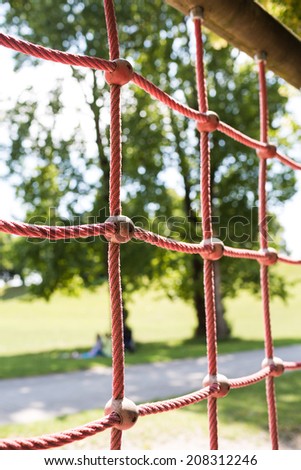 Ropes in children spider web with screw. Detail of cross red ropes in safety climbing outdoor equipment.