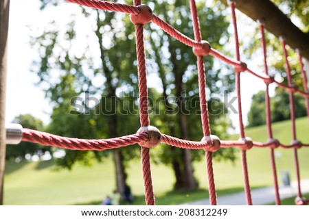 Ropes in children spider web with screw. Detail of cross red ropes in safety climbing outdoor equipment.