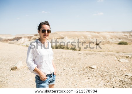 Attractive woman with sunglasses looking at the camera in dramatic valley in the Negev desert in Israel. Free Happy Woman Enjoying Nature or Holiday. Beauty Girl Outdoor. Enjoyment.