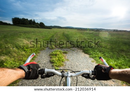 Man biking fast. View from bikers eyes. The end of the road and start of the track. Motion blurred.