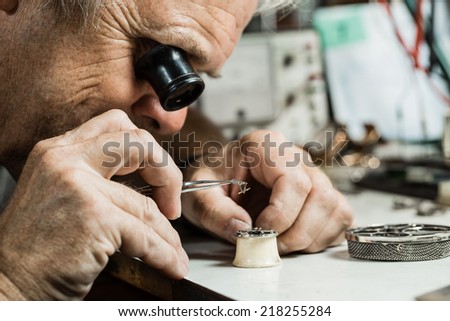 Clockmaker repairing wrist watch.