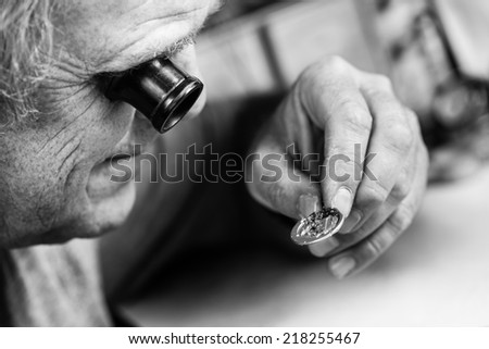 Clockmaker repairing wrist watch. Black and white photography. Selective focus.