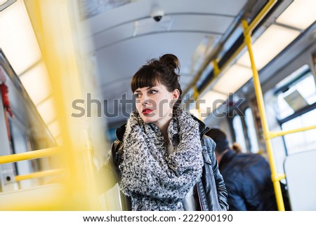 Young woman standing in public transportation transit in train or tramway. Color toned image. Selective focus.