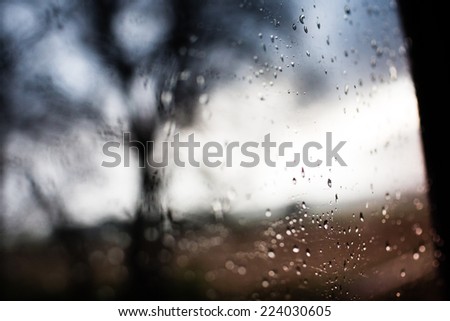 Drops of rain on the train window with tree in background. Dramatic sunrise. Color tone image.