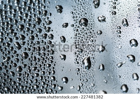 Drops of rain on window with lights background. Color toned image.