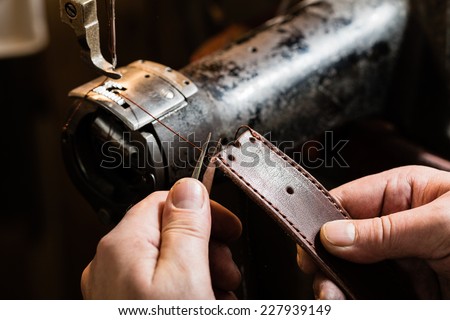 Sewing process of the leather belt. Man\'s hands behind sewing.