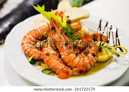 Saute shrimps with vegetables and lemon on white plate in the restaurant.