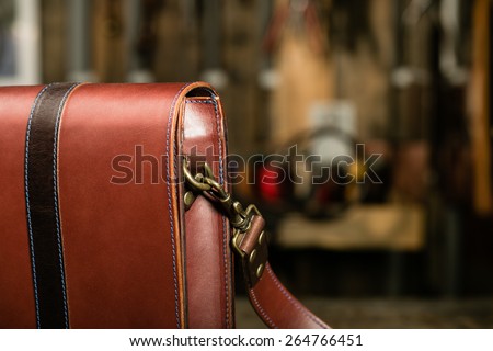 Detail of leather bag in the leather workshop on working desk with blurred background.