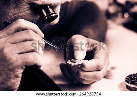 Clockmaker repairing wrist watch. Selective focus. Monochrome cream tone. Black and white photography.
