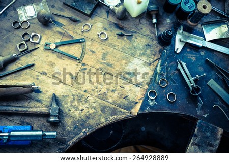 Working desk for craft jewelery making with professional tools. Grunge wooden table. View from above. Copy space.