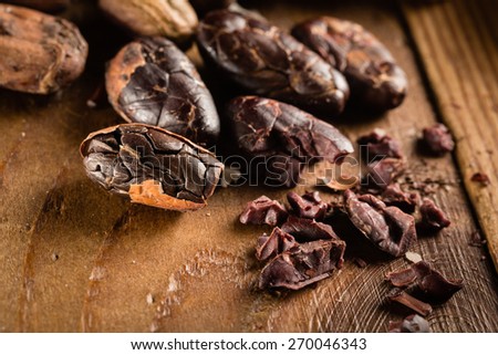 Macro detail of grunge cocoa beans on the wooden table or desk in the kitchen.