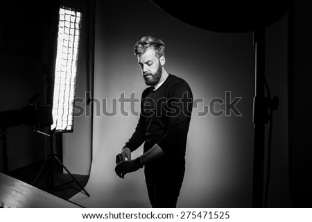 Young bearded man posing against black background at photo studio. Black and white photography.