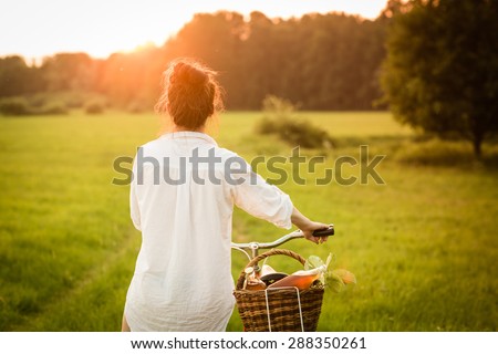 Woman riding bicycle with the basket of fresh. Color toned image.