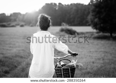 Woman riding bicycle with the basket of fresh food. Black and white photography.