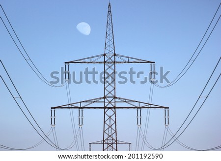 Symmetrical view on a high voltage power line. The moon is visible in the background.