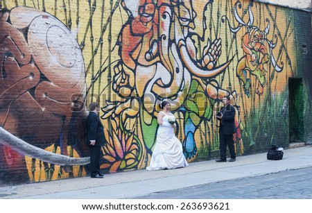 Brooklyn, NY, USA - November 21, 2010 - Wedding Photographer with Bride and Groom.  Wedding Photographer takes his Clients to Dumbo Brooklyn for a fabulous Graffiti Wall Background.